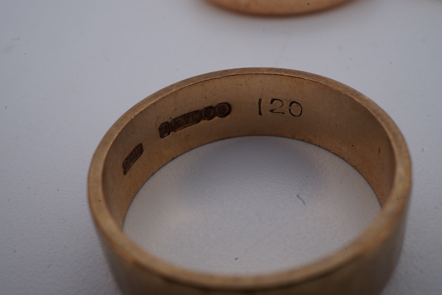 Four gold rings, comprising: a 22ct gold wedding band, size M, British assay marks, gross weight 3 grams; a 9ct gold band with a panelled finish, size N, British hallmarks, gross weight approximately 3.5 grams; a bicolou